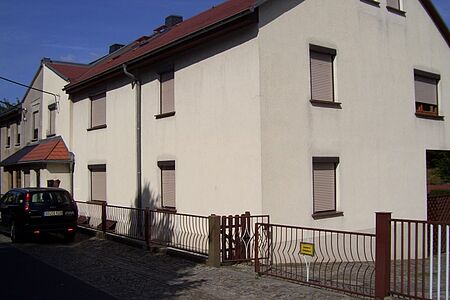 Doppelhaus mit weißer, sanierungsbedürftiger Fassade