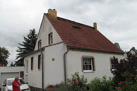 Kleines Einfamilienhaus mit sanierungsbedürftiger Fassade in schmutzigem Weiß