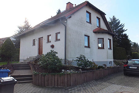 Weißes Einfamilienhaus mit Grünspan auf der Fassade