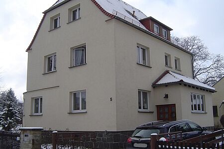 Dreistöckige Villa mit Krüppelwalmdach und schmutzig-weißer Fassade