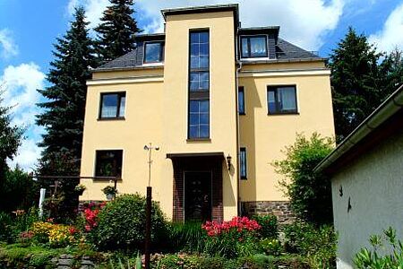Dreistöckiges Einfamilienhaus mit moderner gelblicher Fassade.