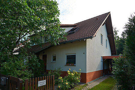 Einfamilienhaus mit hellblauer Fassade und orangen Fundament