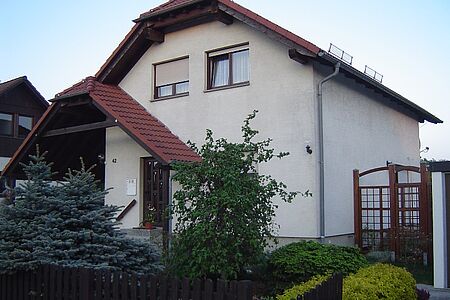 Einfamilienhaus mit angrenzendem Carport und schmutzig-weißer Fassade