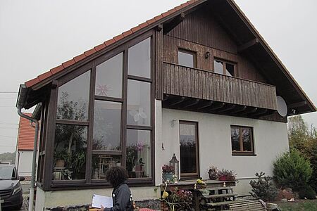 Einfamilienhaus mit Holzvertäfelung und Balkon sowie mit verglaster Fensterwand