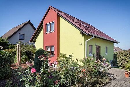 Grünes Wohnhaus mit roten Elementen auf der Fassade