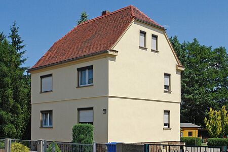 Dreistöckiges Haus mit pastellgelber Spezialputzfassade