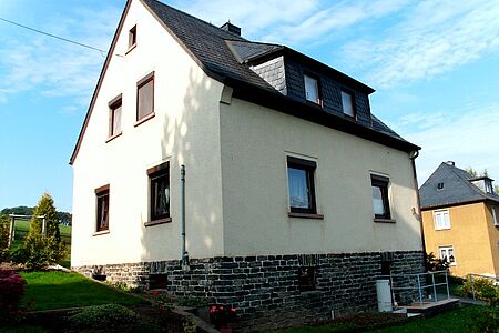 Rückseite eines Hauses mit Witterungsschäden an der Fassade unterhalb der Fenster