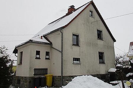Wohnhaus mit drei Etagen und beiger, stark verschmutzter Fassade 