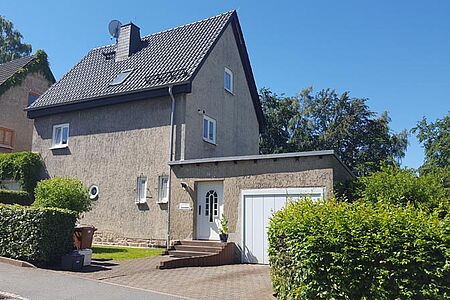 Graubraun verputztes Wohnhaus mit drei Etagen und kleinen Fenstern