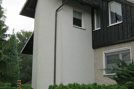 Hohes Wohnhaus mit spitzem Dach und frischer Fassade in Schwarz, Beige und schmutzigem Weiß