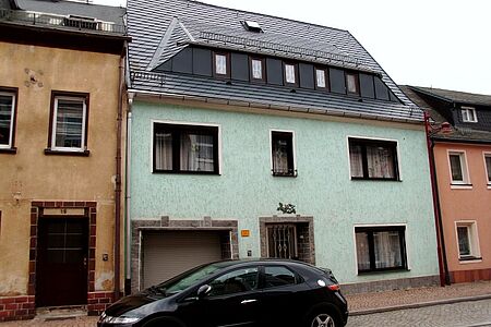 Weißgrüne Fassade eines Reihenhauses mit vielen kleinen Rissen