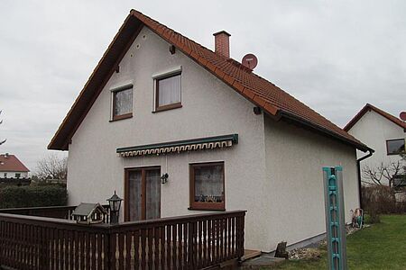 Weißes Wohnhaus mit grau-verwitterter Fassade