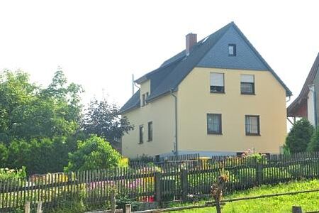 Dreistöckiges Haus mit gelber Fassade und dunkelblauem Dach