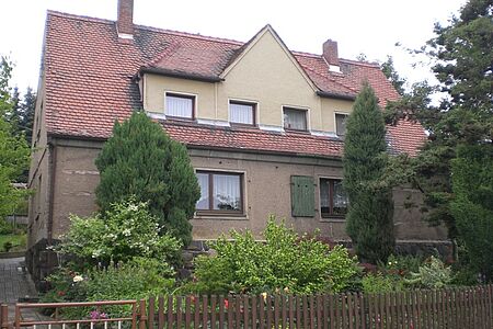 Zweifamilienhaus im Grünen mit veralteter Fassade in Beige und Braun