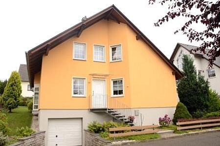 Großes Einfamilienhaus mit Treppe zum Eingang und gelber Fassade