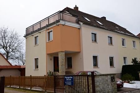 Mehrstöckiges Mehrfamilienhaus mit Balkon und Fassade in drei verschiedenen Orangenuancen