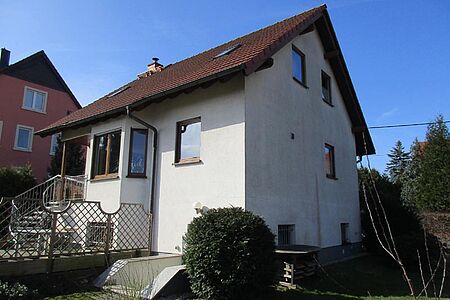 Wohnhaus mit schmutzig-weißer Fassade, geschwungenem Treppenaufgang und Erker im Eingangsbereich