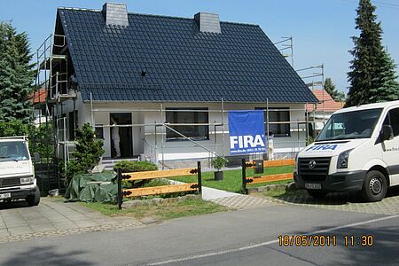 Weißes Einfamilienhaus während der Fassadensanierung mit Gerüst