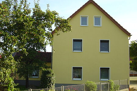Dreistöckiges Wohnhaus mit gelblich-grüner Fassade