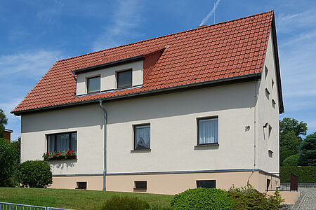 Doppelhaus mit hellgrauen, frisch gestrichenen Fassaden und einem pastellorangen Fundament