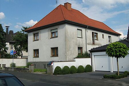Mehrfamilienhaus mit Walmdach und verwitterte Fassade in hellem Blau 
