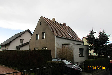 Ehemals weißes Einfamilienhaus mit verwitterter Fassade