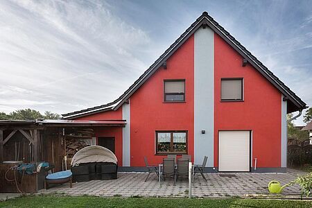Knallrotes Wohnhaus mit hellgrauen Elementen auf der Fassade