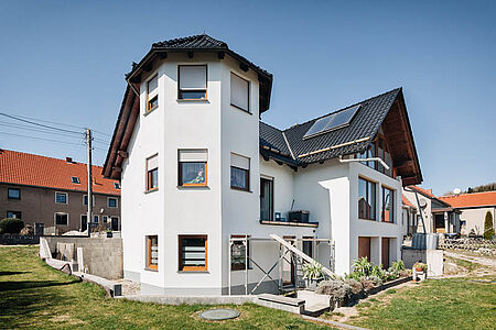 Großer Neubau mit Satteldach, Erkerturm und strahlend-weißer Fassade