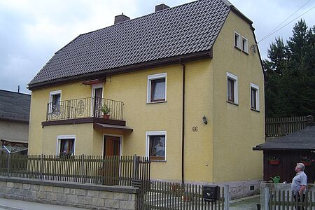 Dreistöckiges Wohnhaus mit Walmdach mit leicht veralteter und verschmutzter Fassadenbeschichtung vor der Sanierung