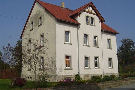 Dreistöckiges Mehrfamilienhaus mit Flecken auf der Fassade vor der Sanierung