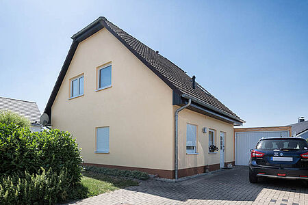 Wohnhaus mit helloranger Fassade und angebauter Garage