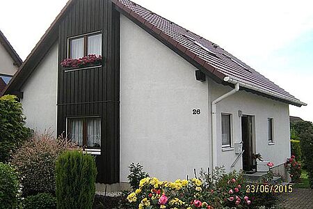 Wohnhaus mit leicht verschmutzter, weißer Fassade und vertäfelten Elementen