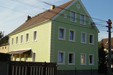 Mehrfamilienhaus mit vielen Fenstern und hellgrüner Fassade