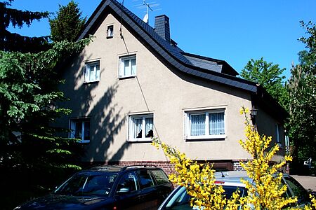 Gräuliche Fassade eines Einfamilienhauses – Gardinen an Fenstern zugezogen
