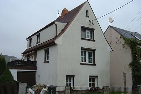 Haus mit spitzem Satteldach und verschmutzter weißer Fassade