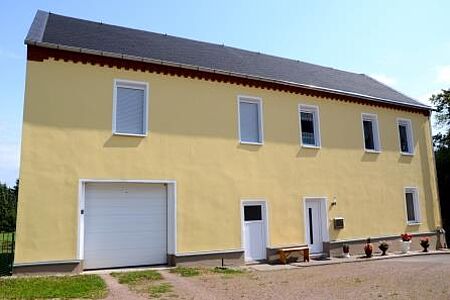 Einfamilienhaus mit blassgelber Fassade und kleiner Garage 