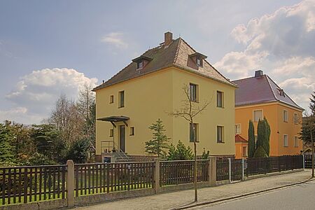 Gelbes, mehrstöckiges Wohnhaus mit frischem, ebenmäßigem Anstrich und Walmdach