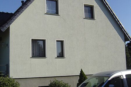 Einfamilienhaus mit gräulichem, leicht fleckigem Putz