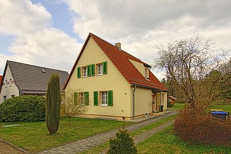 Wohnhaus mit frischer, hellgelber Fassade und grasgrünen Holzfensterläden