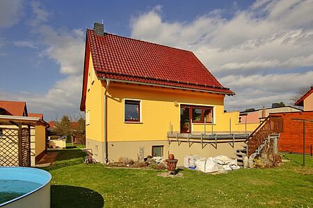 Einfamilienhaus mit beige gestrichenem Fundament und frischer Fassadenbeschichtung in sonnigem Gelb