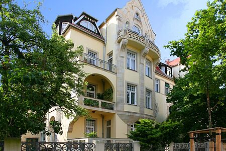 Sanierte Altbauvilla mit hellgelbem Anstrich und Balkonen
