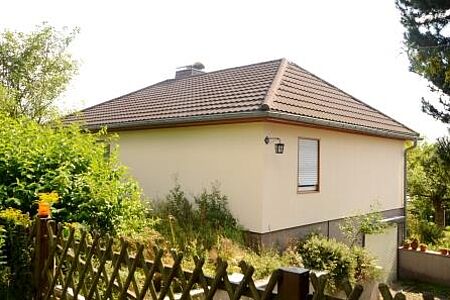 Einfamilienhaus mit sanierter Fassade im ersten Stock und Garten rundherum