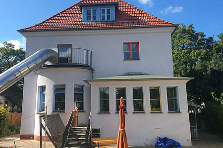 Kindergartengebäude mit leicht beschädigter heller Fassade