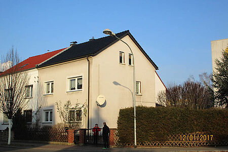 Abschnitt eines Hauses mit stark verwitterter, bröckelnder und fleckiger Fassade