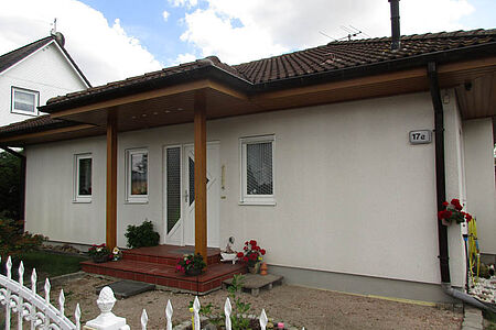Weißes Bungalow mit Walmdach und leicht verschmutzter Fassade