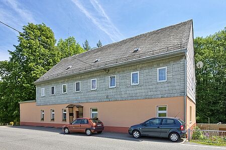 Mehrfamilienhaus mit orangener Fassade im unteren Stockwerk