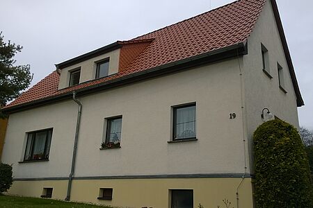 Doppelhaus mit hellgrauen Fassaden und einem gelben Fundament