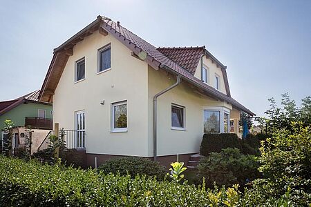 Frisch gestrichenes, eierschalenfarbenes Einfamilienhaus mit Krüppelwalmdach