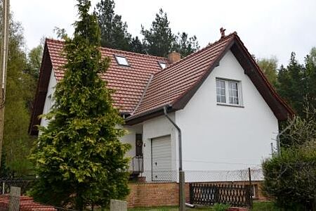 Verwinkeltes Wohnhaus mit frischer, weißer Fassade im Grünen
