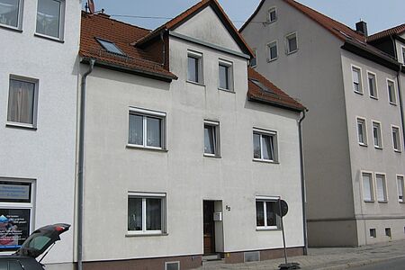 Reihenhaus mit grau-weißer Fassade und grauen Witterungsspuren in der 2. Etage